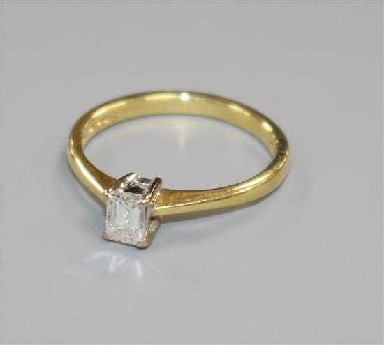 A modern 18ct gold and solitaire emerald cut diamond ring, size J.